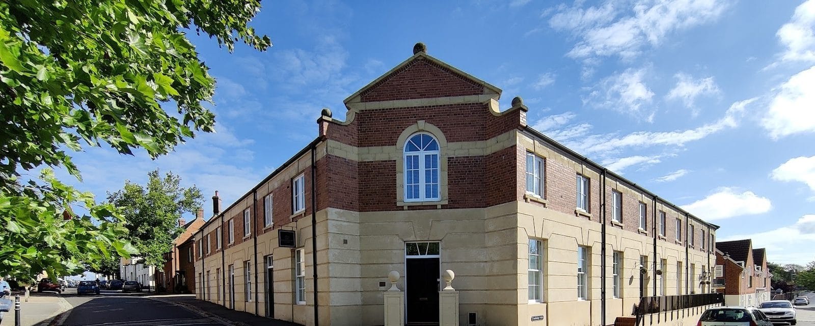 The Poundbury Clinic: a two-storey brick and stone building on a street corner in Poundbury